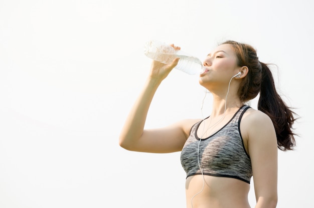 写真 アジアの女性の手で水のボトルを保持していると水を飲む