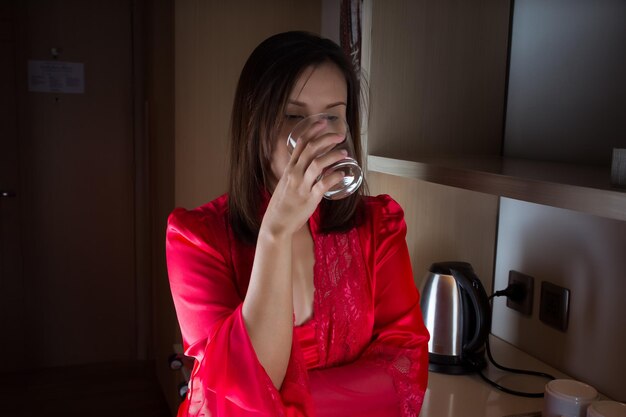 Photo an asian woman is drinking water because of a dry throat in the middle of the night