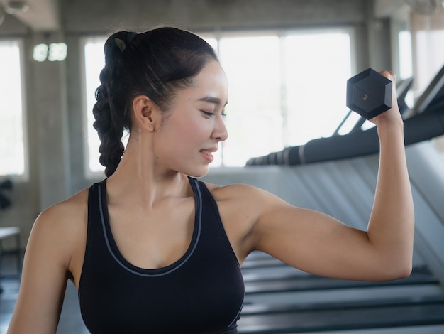 Asian woman is exercising with a dumbbell in gym