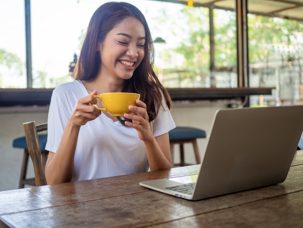 Asian woman is happy to communicate with foreign friends via computers in the coffee shop.