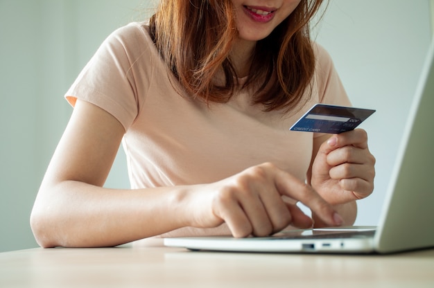 La donna asiatica è felice di utilizzare le carte di credito per lo shopping online