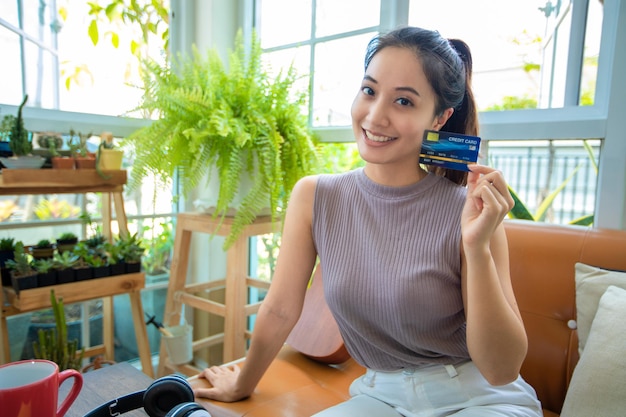 Asian woman is holding credit card and using smartphone shopping online at home. Online shopping  e-commerce  internet banking  spending money  working from home concept