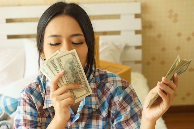Foto la donna asiatica sta baciando i soldi guadagnati da lavoro a casa
