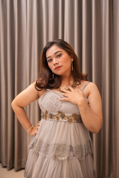 an Asian woman is posing very beautifully while wearing a gold dress and earrings at a wedding