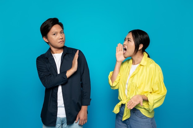 An asian woman is shouting something to a man who is showing a stop gesture with his hand