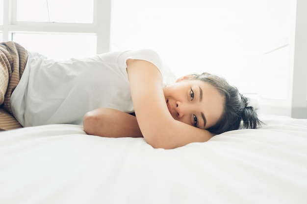 Asian woman is sleeping on her white cozy bed.