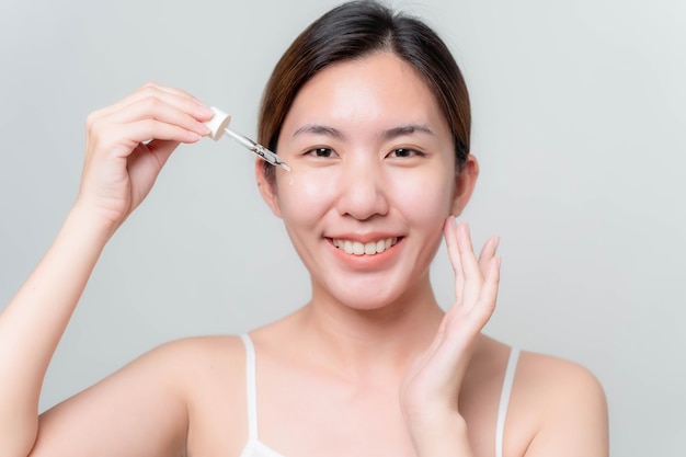 아시아 여성은 피부를 부드럽고 촉촉한 하얗고 투명하게 만들기 위해 얼굴용 피부 세럼을 중단하고 있습니다