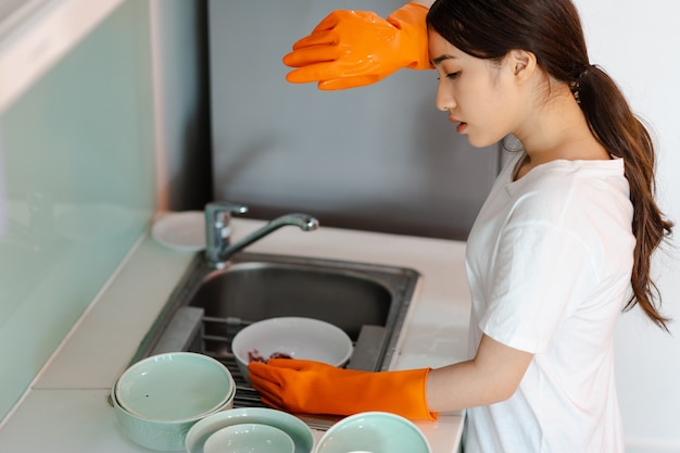 The Asian woman is washing dishes in a tired mood