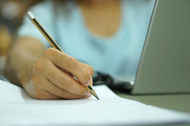 Asian woman jotting down a plan analyzed from a computer on paper