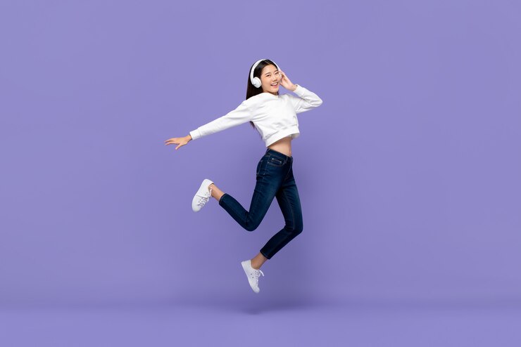Photo アジアの女性のジャンプとヘッドフォンで音楽を聴く