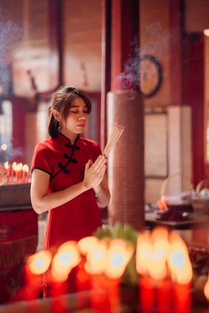 Photo an asian woman lighting incense sticks to pay homage to the chinese new year