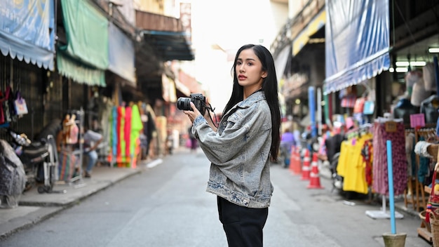 Asian woman looking at camera during her vacation with asian local store in the background