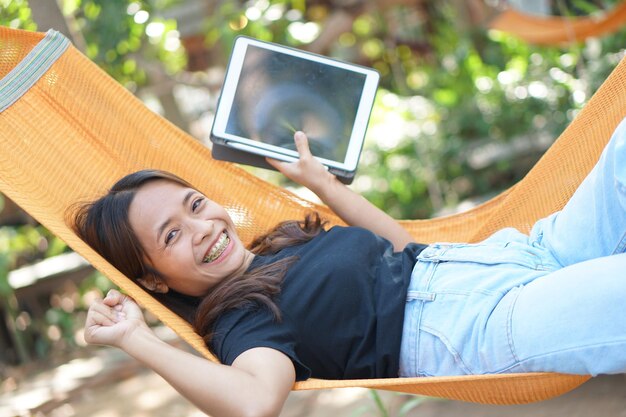 Asian woman looking at earnings on a computer In an orange spread in a coffee shop where she can go to work amidst green nature