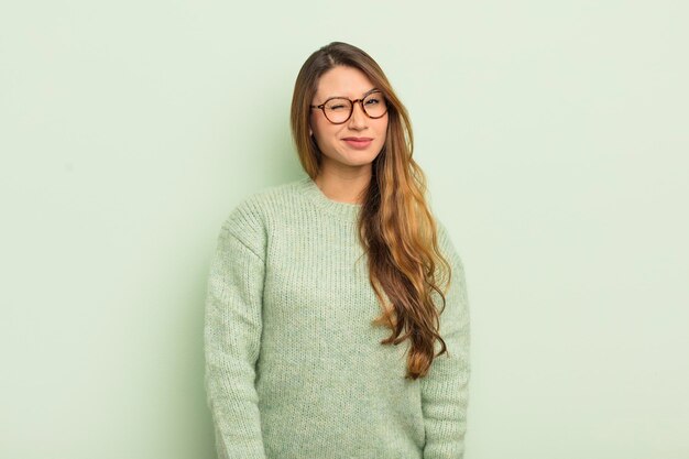 Asian woman looking happy and friendly smiling and winking an eye at you with a positive attitude