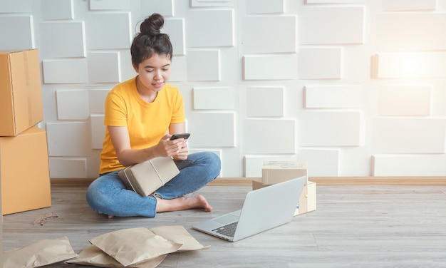 Asian woman looking for order details and checking equipment on laptops and mobile phones