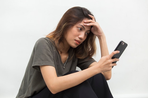 Asian woman looking at smart phone with feeling sad