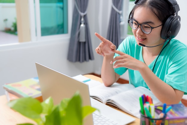 Donna asiatica che cerca di parlare in videoconferenza che chiama su un computer portatile ragazze studenti parlano rispondere con auricolare microfono classe università apprendimento internet online formazione a distanza da casa