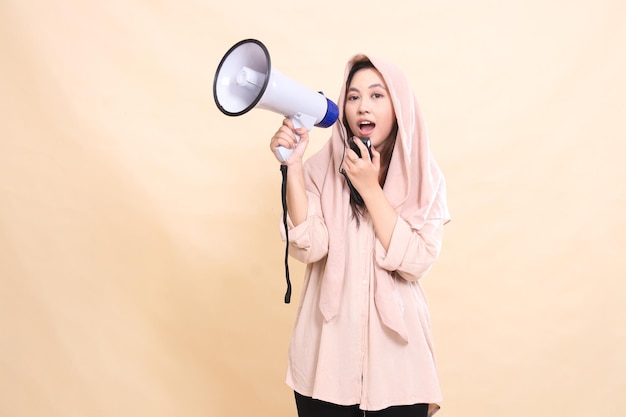Asian woman looks at the camera with her right hand holding audio and holding a megaphone loudspeake