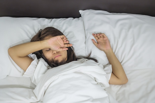 Asian woman lying in bed late at night, young female sleep in bedroom