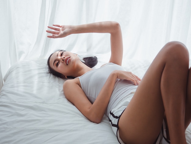 Asian woman lying in white bed