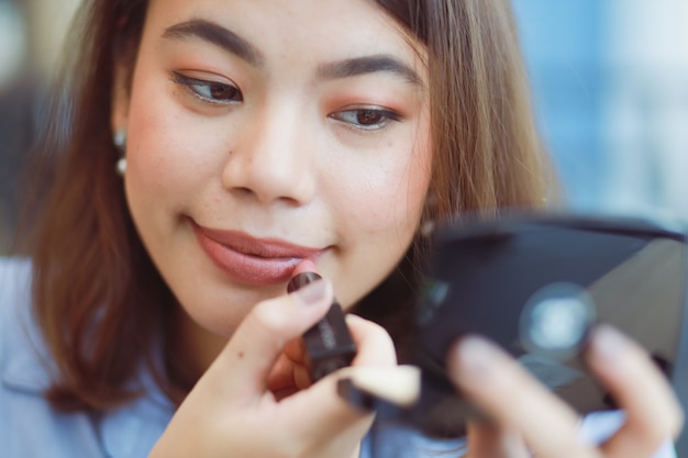 Азиатская женщина макияж ее лицо с помадой в кафе