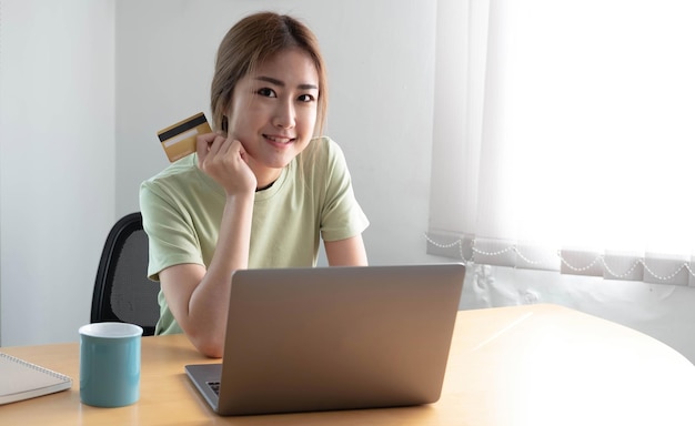 Photo asian woman makes a purchase on the internet on the laptop computer with credit card