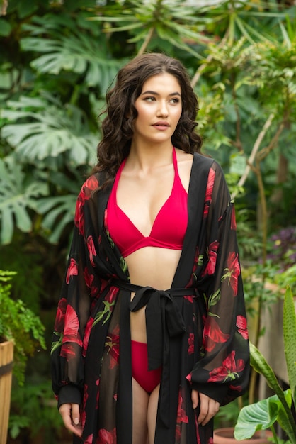 Asian woman near palm trees posing in summer dress on vacation