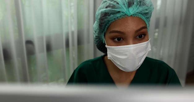 의사 방에 앉아 얼굴 마스크를 쓰고 아시아 여자 간호사