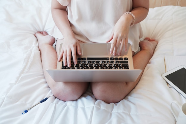 寝室でラップトップを使ってオンラインで仕事や買い物をしているアジアの女性。