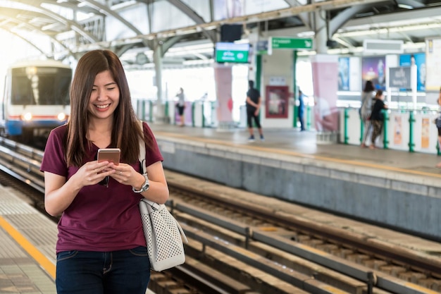 Foto passeggero asiatico della donna con il vestito casuale facendo uso del telefono cellulare astuto