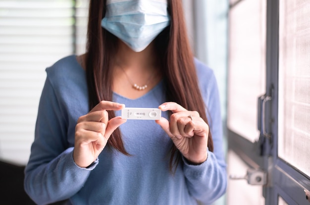 Photo asian woman patient holding positive test result for coronavirus or covid 19 at home