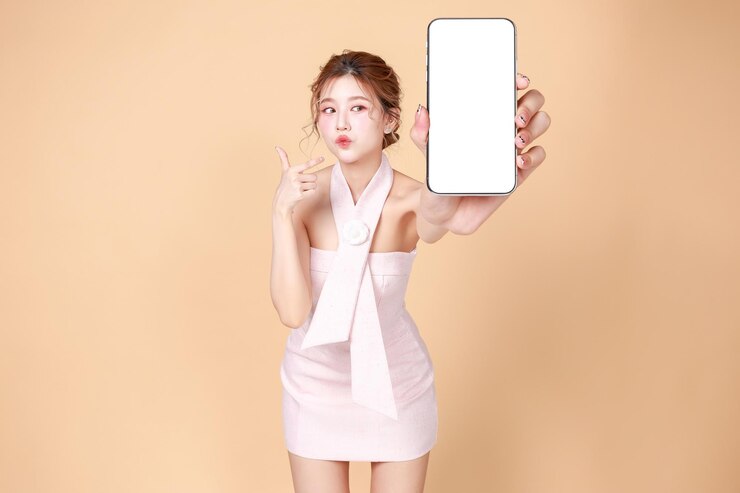 一個穿著粉紅色禮服的亞洲女人拿著白色背景的空白屏幕手機