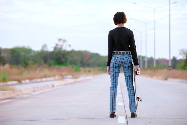 La donna asiatica gioca a skateboard nello stile della ragazza parkpunk