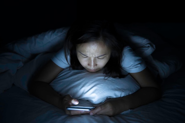 Asian woman play smartphone in the bed at nightThailand people