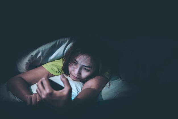 Asian woman play smartphone in the bed at nightthailand\
peopleaddict social mediaplay internet all night