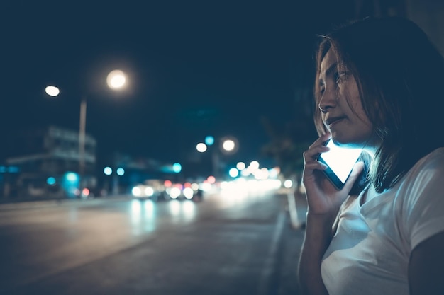 Asian woman play smartphone side road at nightThailand people