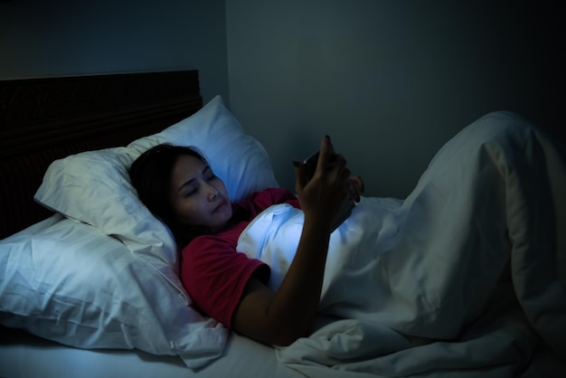 밤에 침대에서 스마트폰으로 게임을 하는 아시아 여성thailand Peopleaddict 소셜 미디어