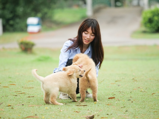 公園で子犬を演じるアジア人女性