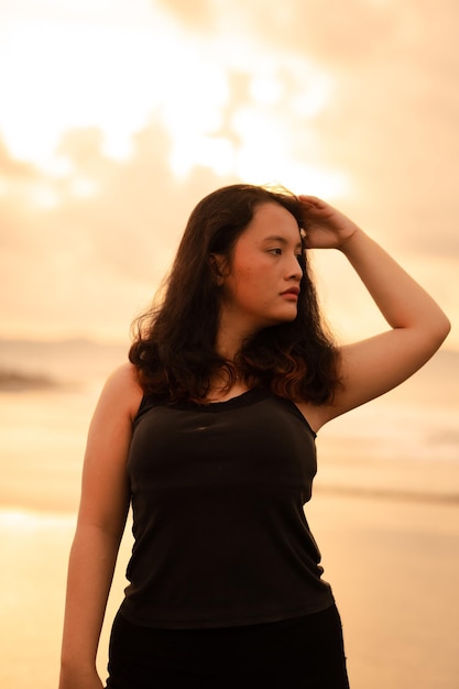 An Asian woman posing very sexy while wearing black clothes on the beach