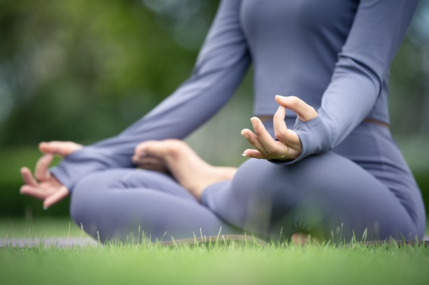 Asian woman practicing yoga in an urban garden