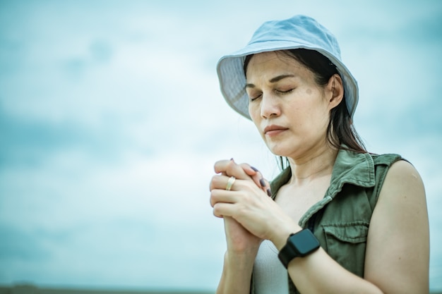 Asian woman praying morning outdoor, Hands folded in prayer concept for faith, spirituality and religion, Church services online concept.