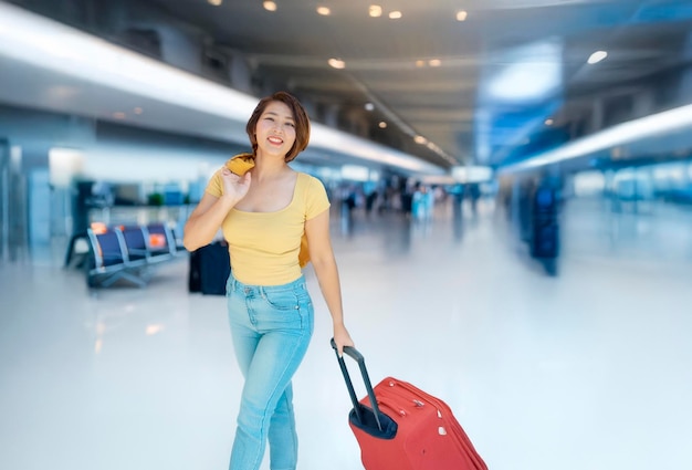 asian woman pulling a suitcase at an airport
