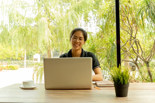 Asian woman puts finger up thinking of idea with laptop in coffee shop.