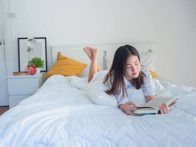 Asian woman reading book on bed in the morning