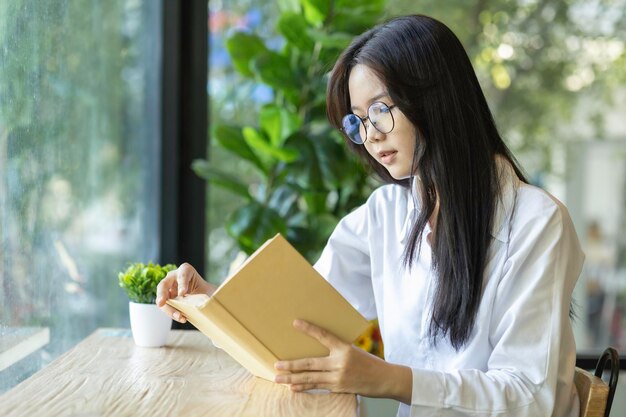 Foto donna asiatica che legge un libro a casa