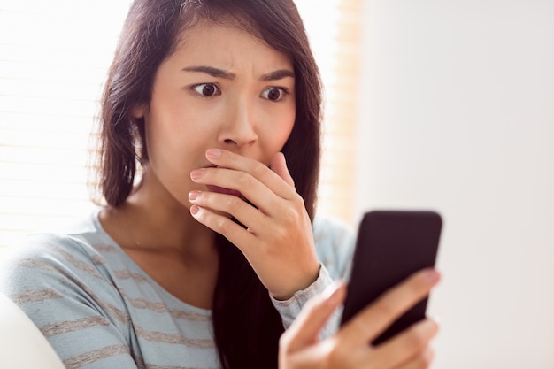 Asian woman reading shocking text