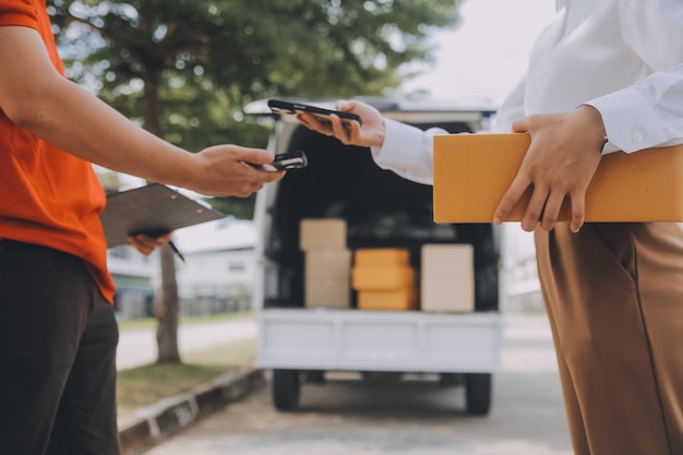 Photo asian woman receiving product from delivery man at home young owner woman order product from smartphone application woman with online business or sme concept