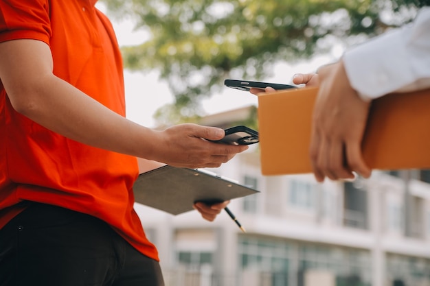 Photo asian woman receiving product from delivery man at home young owner woman order product from smartphone application woman with online business or sme concept