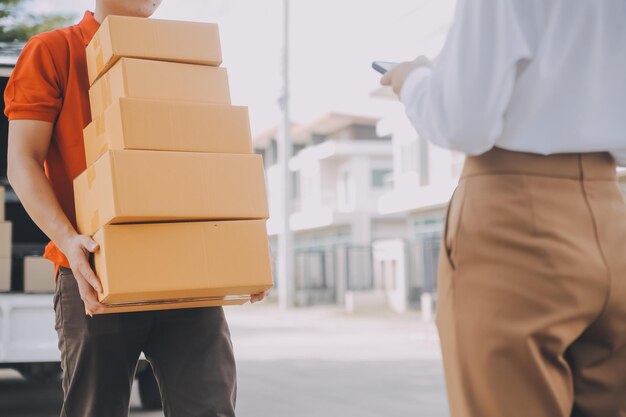 Photo asian woman receiving product from delivery man at home young owner woman order product from smartphone application woman with online business or sme concept