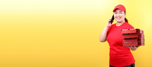 Asian Woman in red cap, giving food order italian pizza in cardboard  boxes isolated holding mobile phone with blank  white  empty screen.